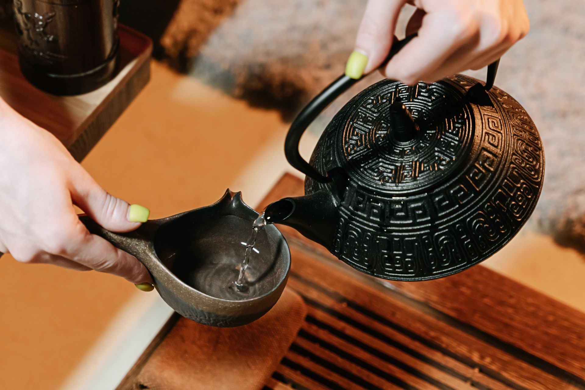 Tea being poured from a cast-iron teapot into a ceramic cup