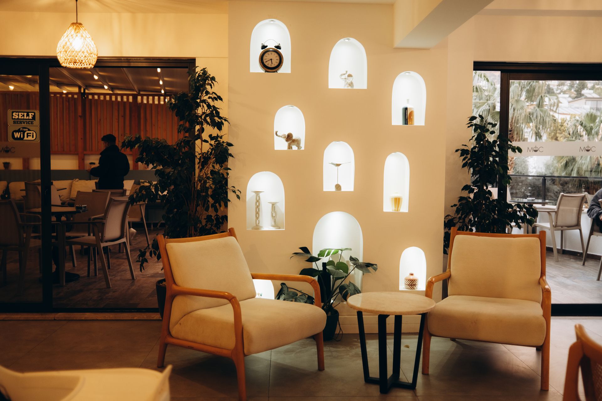 A cafe lounge with two armchairs and lit arched wall niches