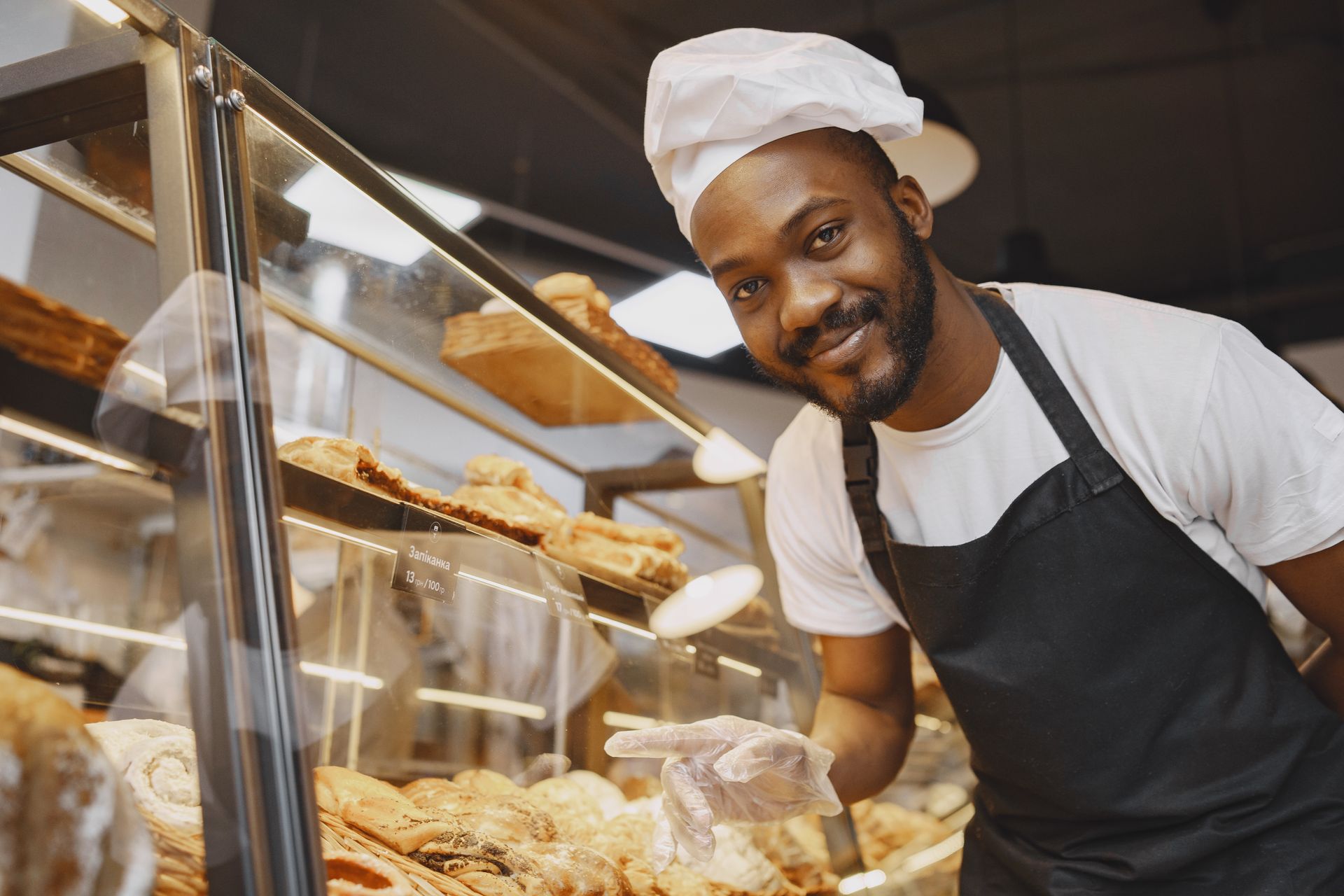 A smiling baker in an apron at a pastry counter